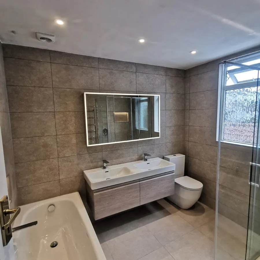 Bathroom with a wood-effect double vanity, lit mirror cabinet and bath