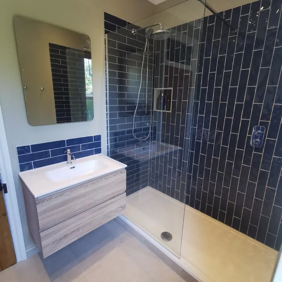 Shower with navy metro tiles, a wood-effect vanity and blue tiled splashback