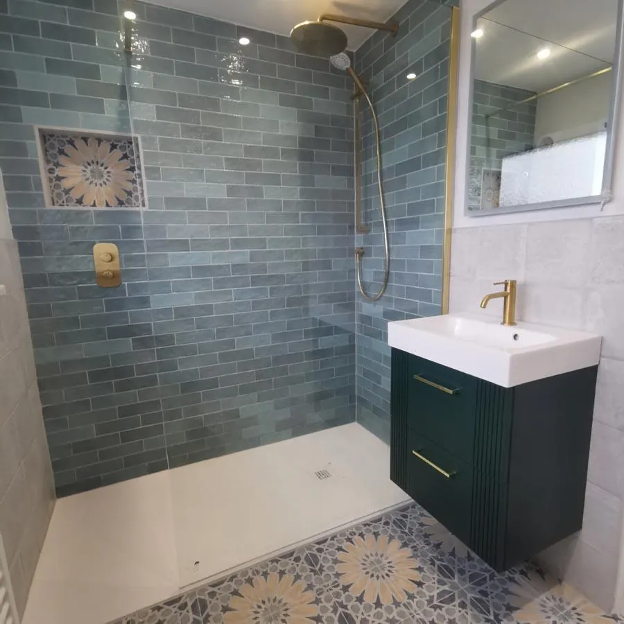 Shower with green metro tiles, a brass shower and a dark green vanity unit
