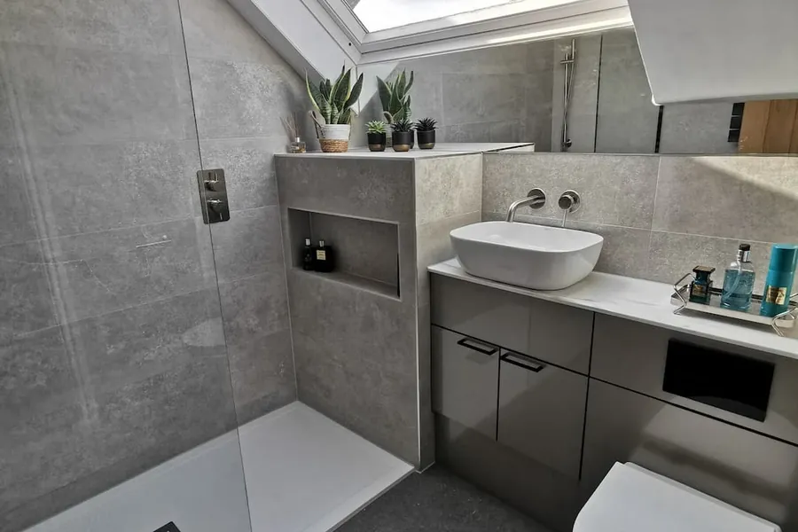Bathroom with a tiled shelf, a basin on a grey vanity unit and a walk-in shower
