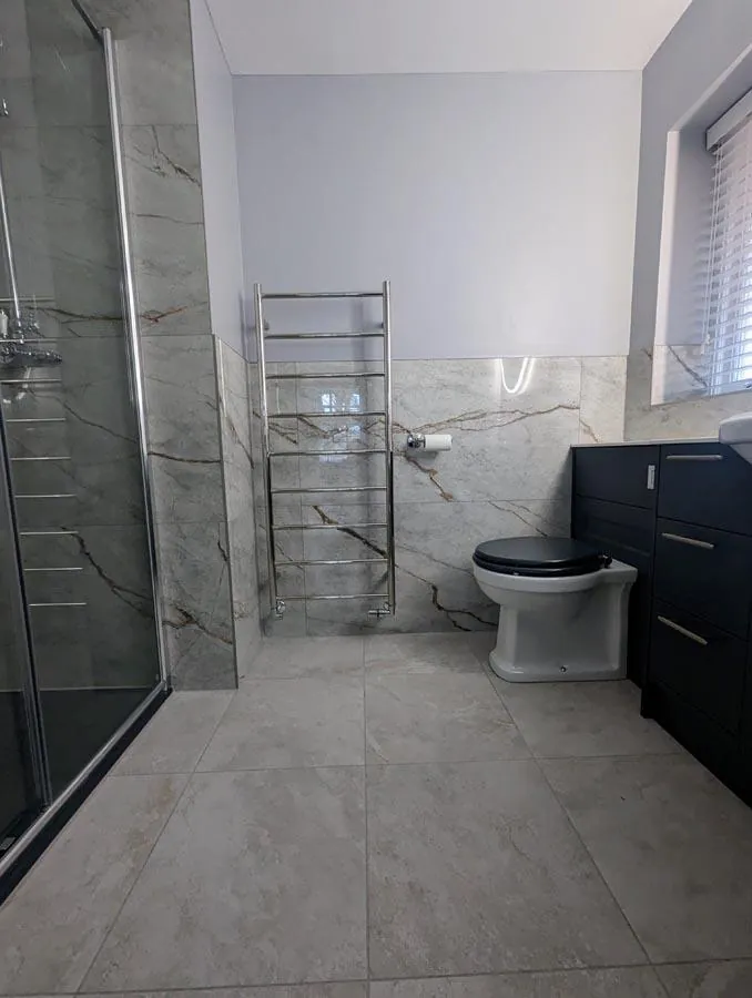 Bathroom with a walk-in shower, chrome towel rail and dark vanity unit