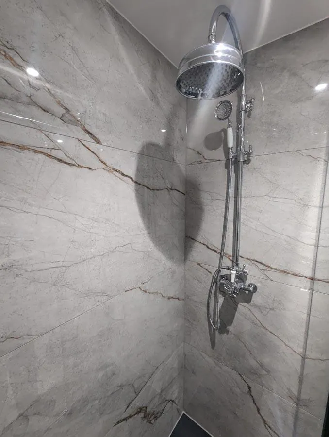 Marble-effect shower wall with a chrome rainfall shower