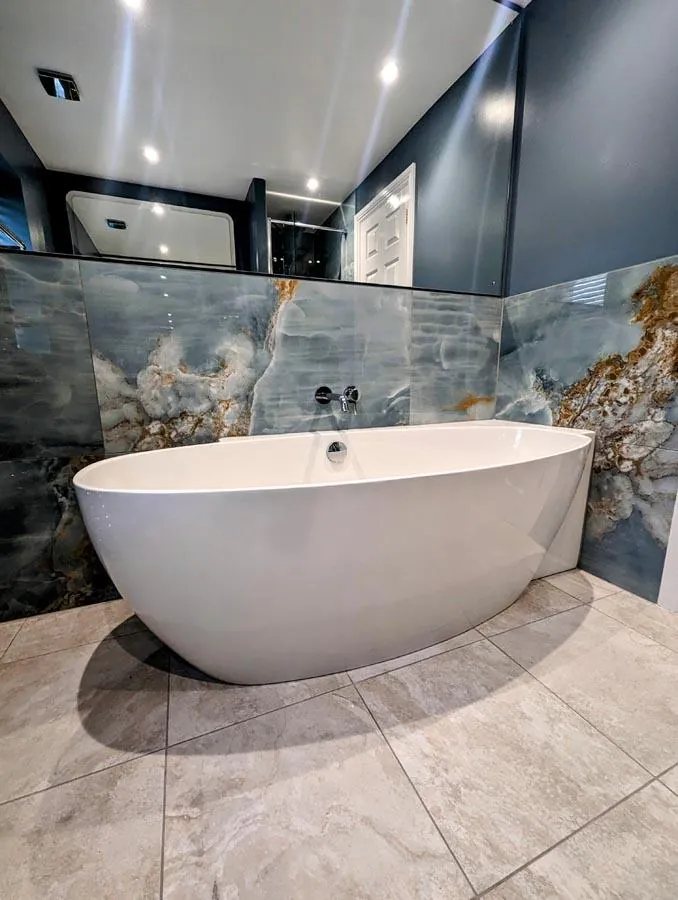 Freestanding bath against a large-format marble-effect feature wall