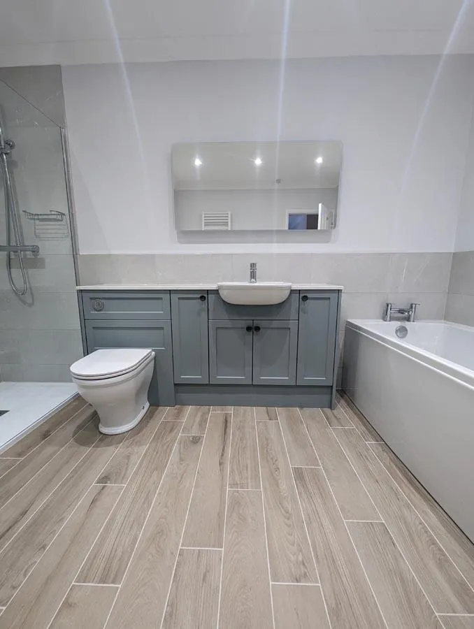 Bathroom with wood-effect floor tiles, a grey-blue vanity unit and bath
