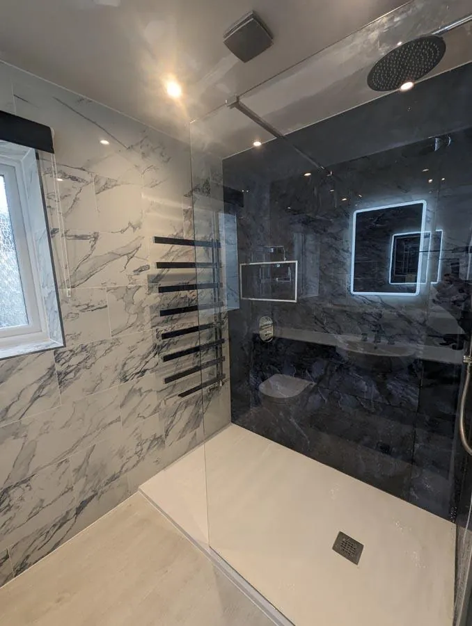 Walk-in shower with dark marble-effect walls and a black towel radiator