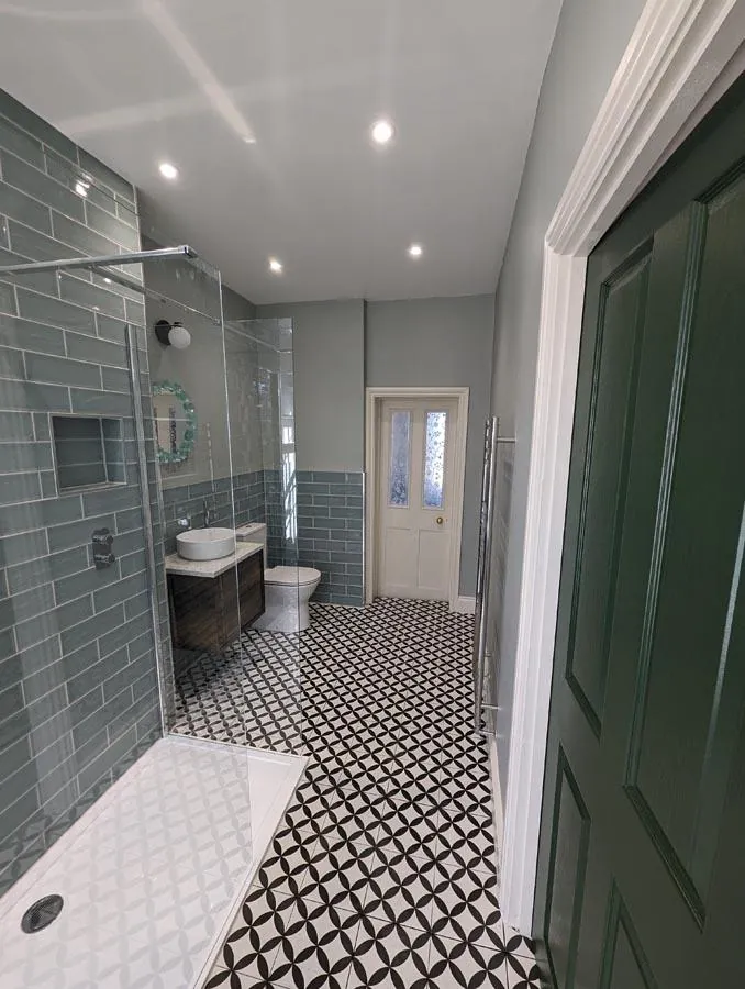 Bathroom with green tiles, a geometric floor and a walk-in shower