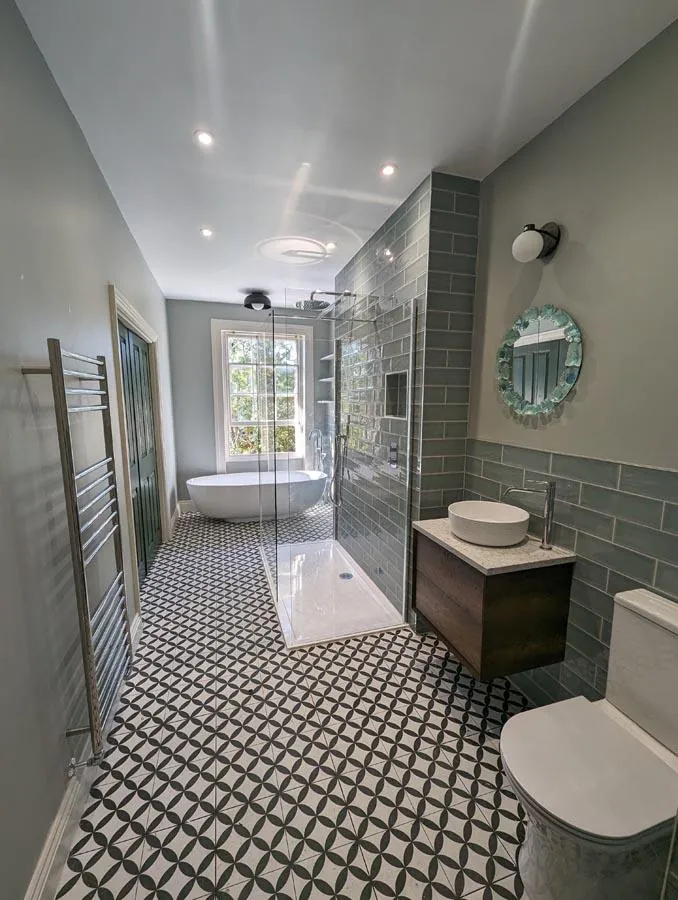 Bathroom with green tiles, a round mirror and a wood vanity unit