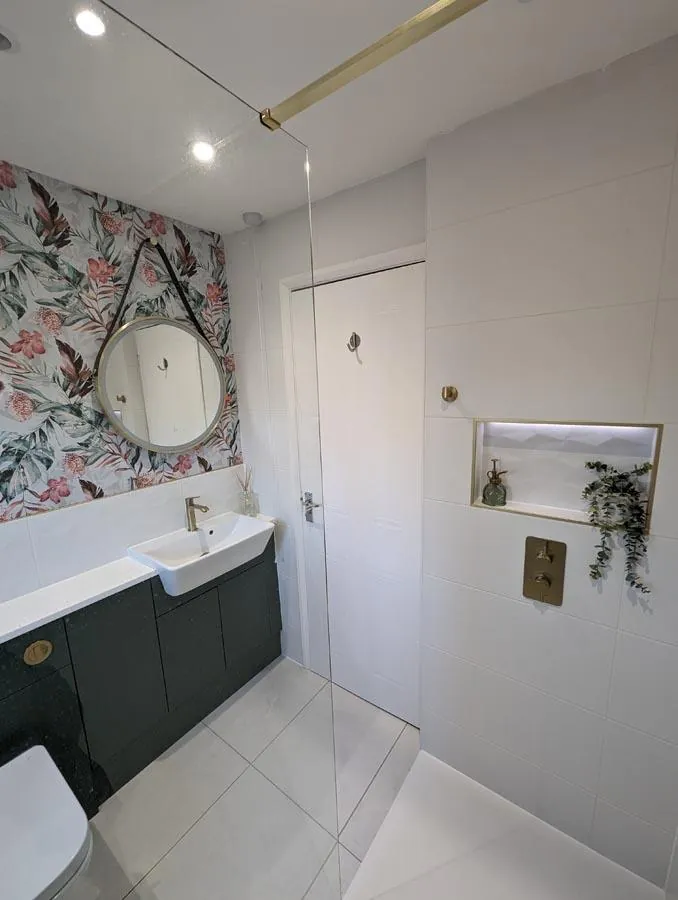 Bathroom with a floral feature wall, round mirror and dark green vanity unit